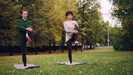 two women practicing yoga outdoors in autumn