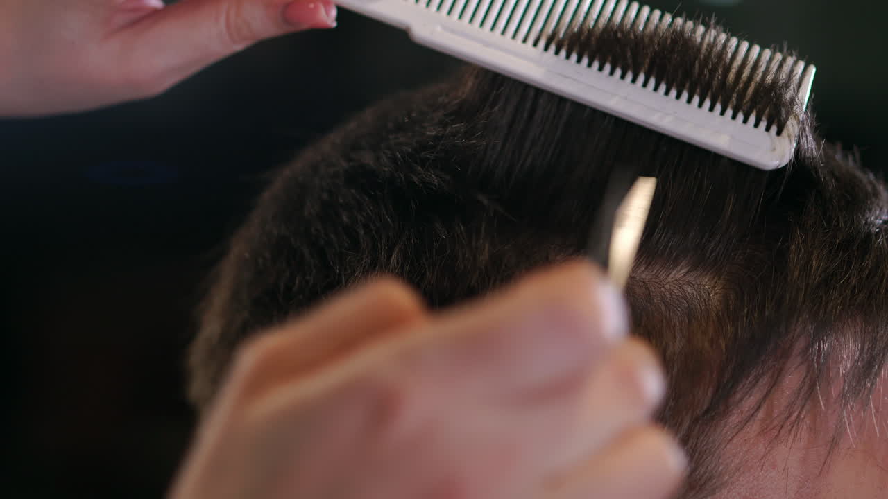 Close up of men's hair cutting scissors in a beauty salon. Frame. Close up of a haircut at a hair saloon. Professional barber styling hair of his client