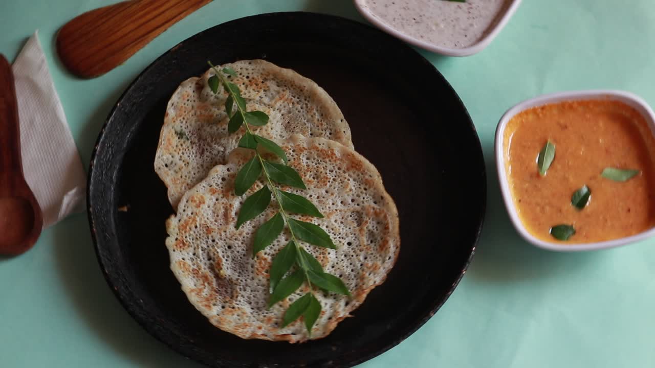 oothappam giratorio - dosa - desayuno del sur de la india con arroz, lentejas y verduras servidas con chutney de coco aislado sobre fondo verde