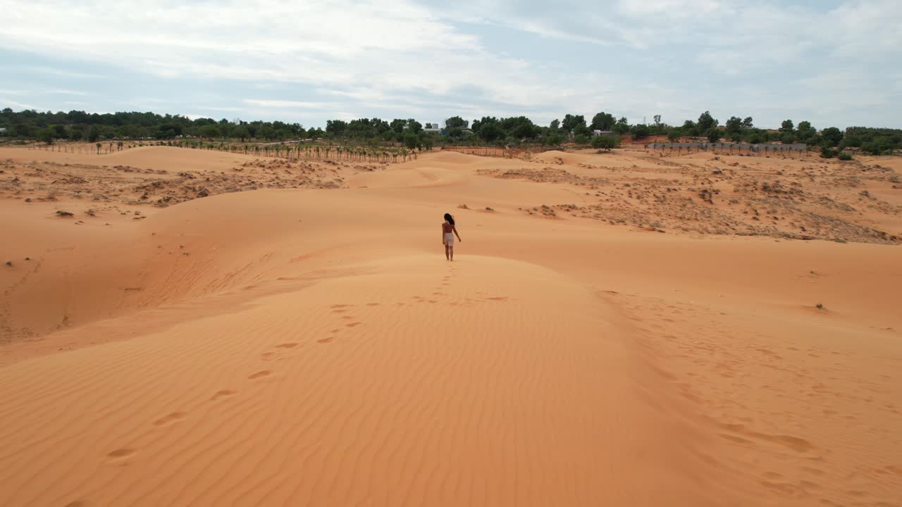 베트남 무이네의 모래사장에서 사막의 모래언덕 위를 걷는 공중 추적 여성