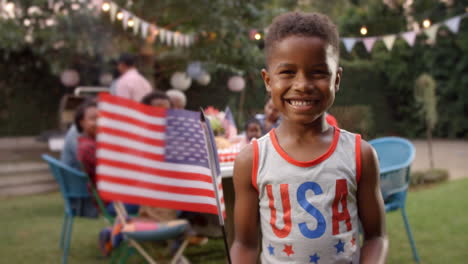 young black boy waving us flag at 4th july family barbecue