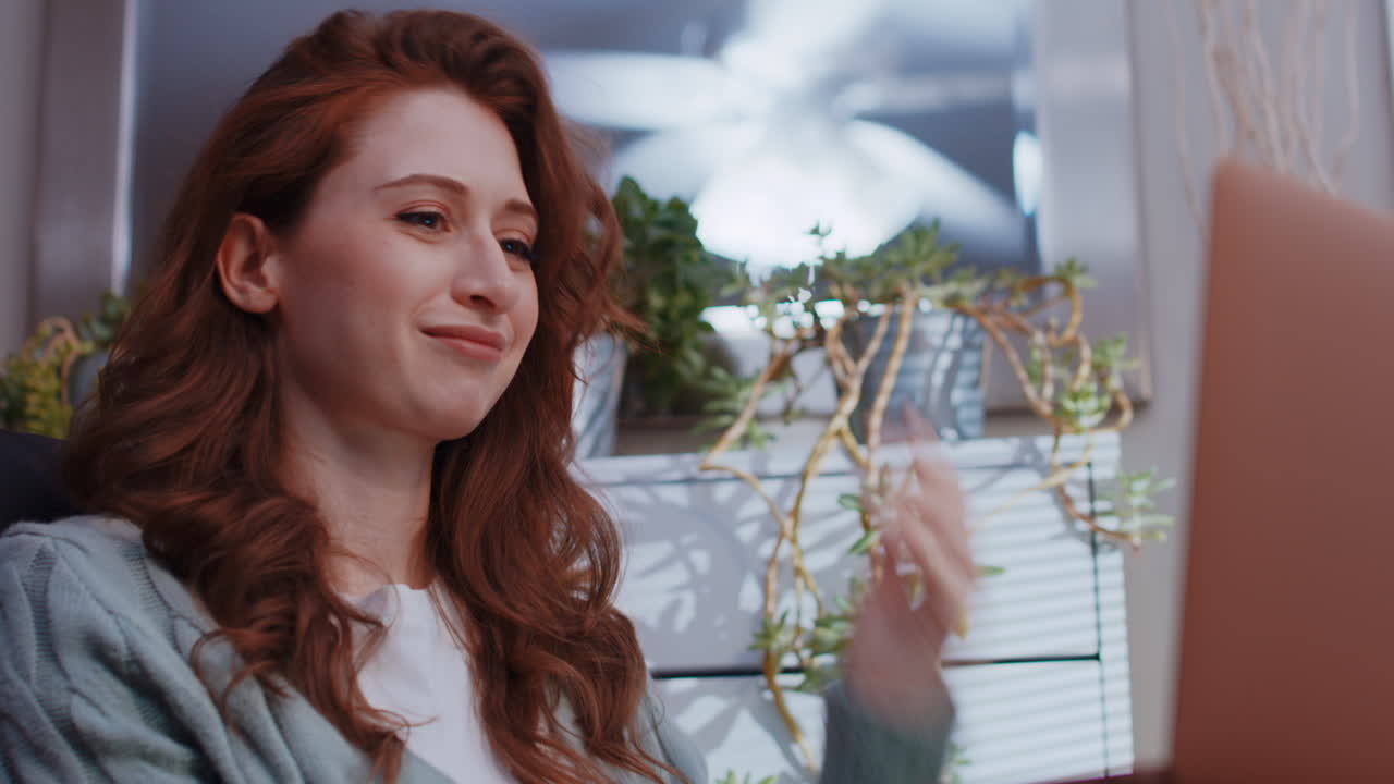 젊은 백인 여성이 노트북에서 집에서 일하면서 비디오 통화를 통해 논쟁하고 있습니다.