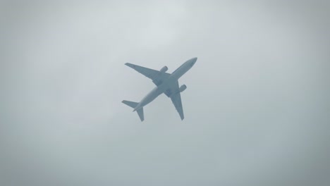 close-up of an airplane flying low in the sky above people in slow motion