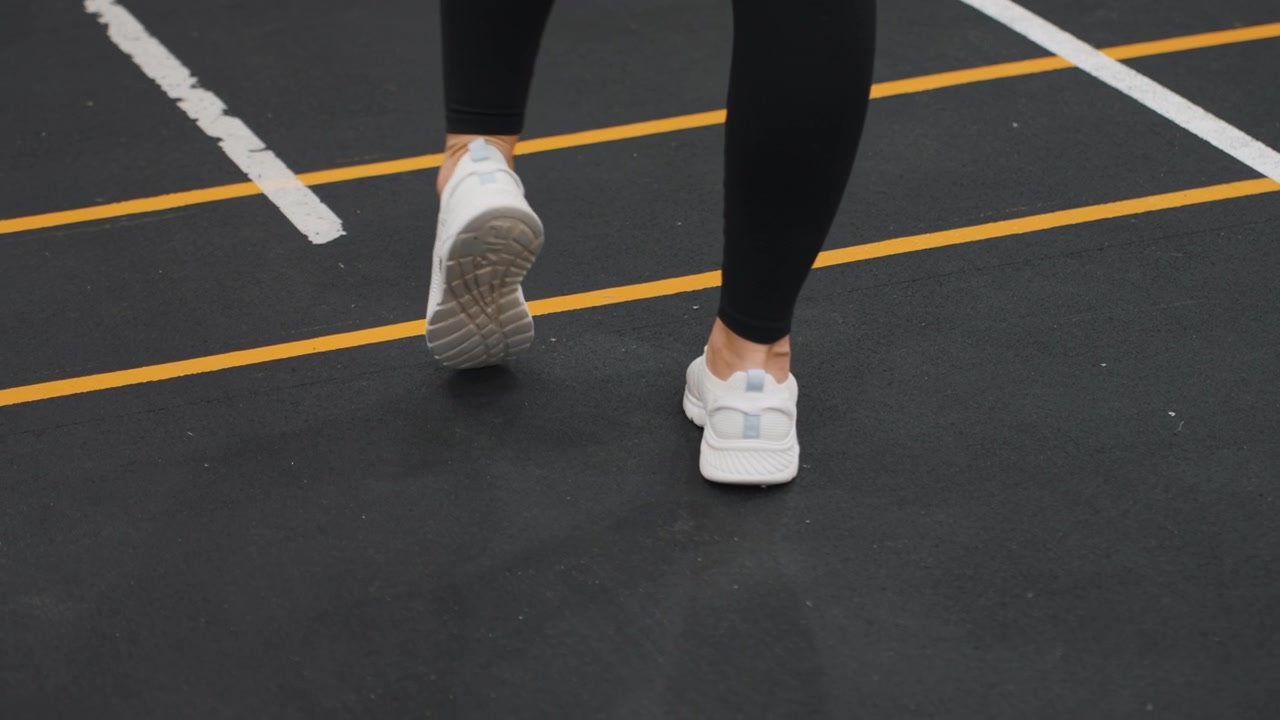 Kapalı bir badminton kortunda, kontrollü yürüme soğuma adımları atan bir sporcu, işaretli çizgiler boyunca yavaş ve ölçülü bir tempoyla hareket ediyor. Sakin atmosfer, yoğun bir antrenman sonrası hareketliliği, nefes almayı ve nazik toparlanmayı vurguluyor.