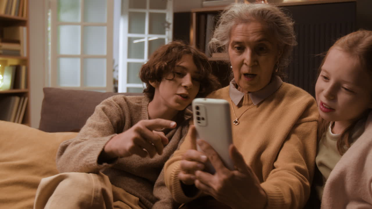 Grandmother and Grandchildren Using Phone on Couch