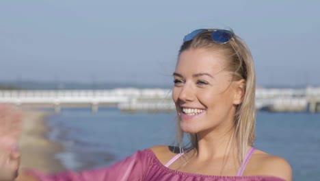 a pretty blonde woman on the beach notices and waves to her friends with a beautiful smile