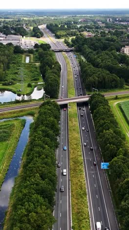 Aerial view of a multi-lane highway with surrounding green landscape and infrastructure