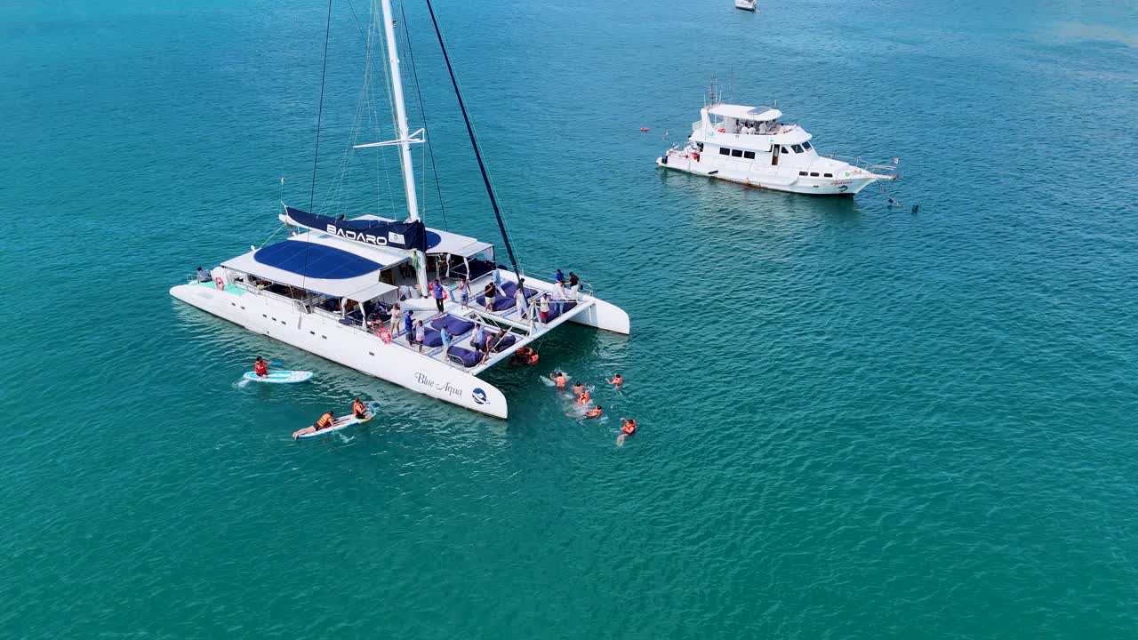 Aerial view of a catamaran and swimmers enjoying the turquoise waters of Phuket, Thailand, under clear skies