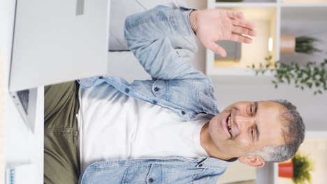 vídeo vertical de un hombre mirando una computadora portátil aplaudiendo.