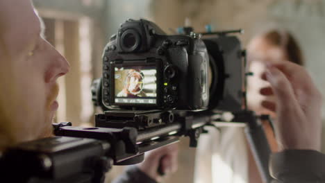 close up view of a cameraman recording a scene of a redhead girl in a ruined building