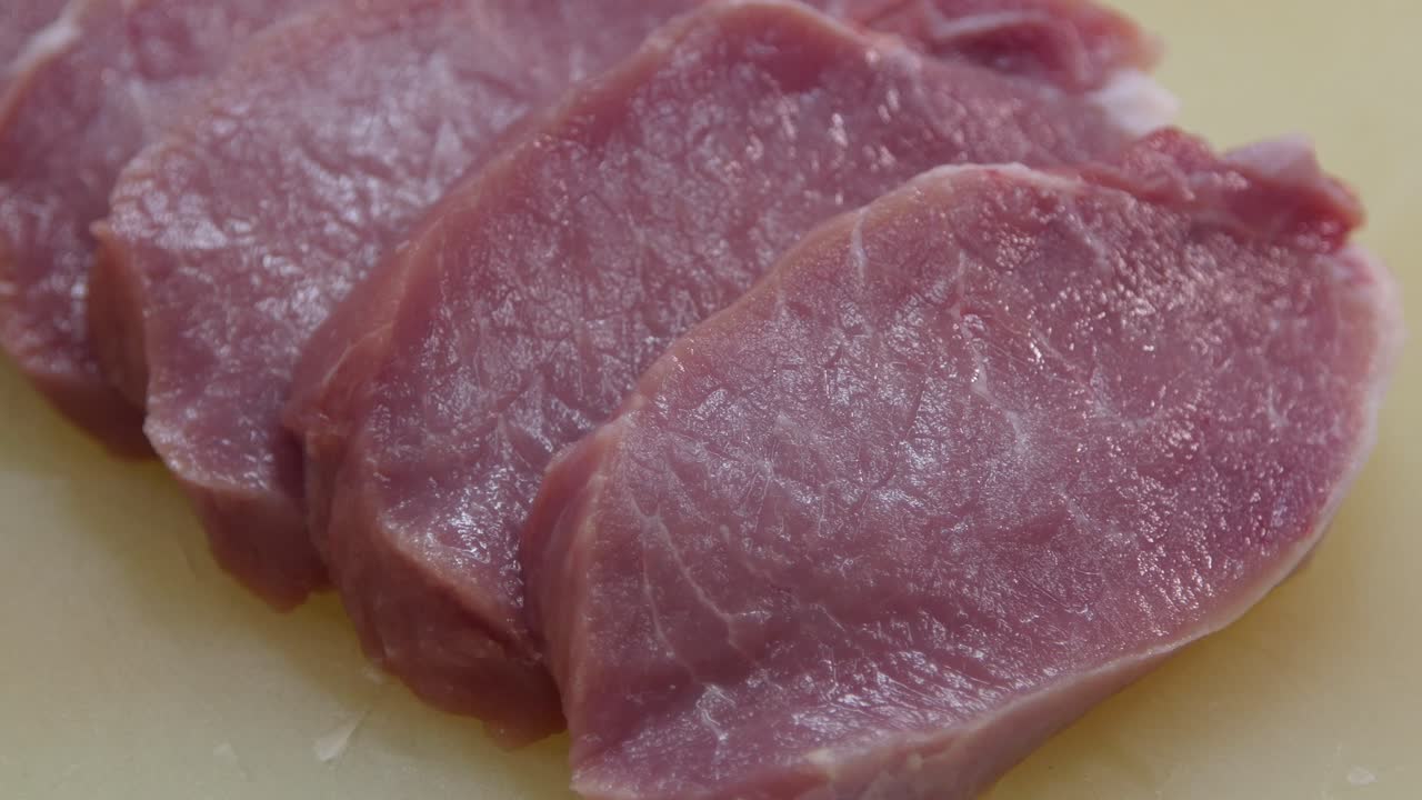 Sliced raw pork chops lying on the chopping board. Close up
