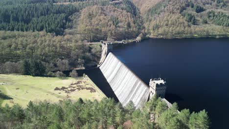 Aerial-view-of-water-cascading-over-the-Derwent-Dam,-Peak-District-UK-revealing-the-landscape-and-Ladybower