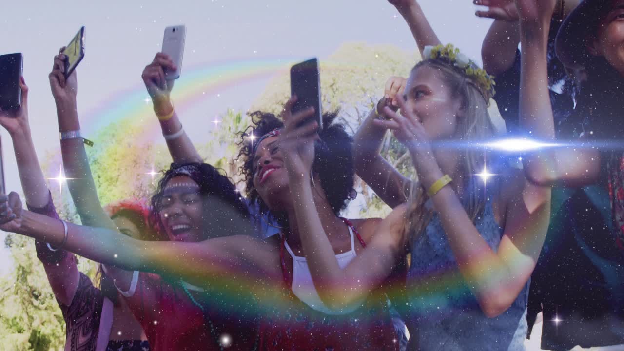 Kvinder på forreste række løfter smartphones for at optage koncert, hepper med glimt, der fejer hen over publikum