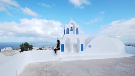 niña sentada en la parte superior de la iglesia blanco-azul, vista del mar egeo