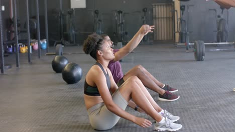 diverse group fitness class training in pairs with medicine balls at gym, in slow motion