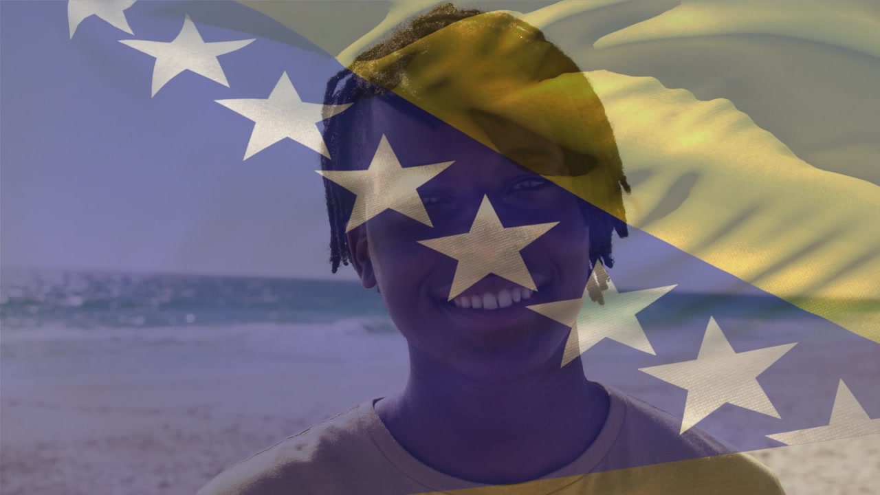 Flag of bosnia and herzegovina over portrait of african american young man with dreadlocks at beach