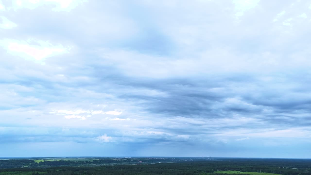 Stormy clouds flowing over flat Lithuanian landscape, aerial time lapse view