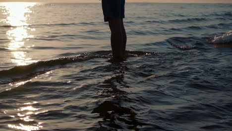person standing in ocean water at sunset