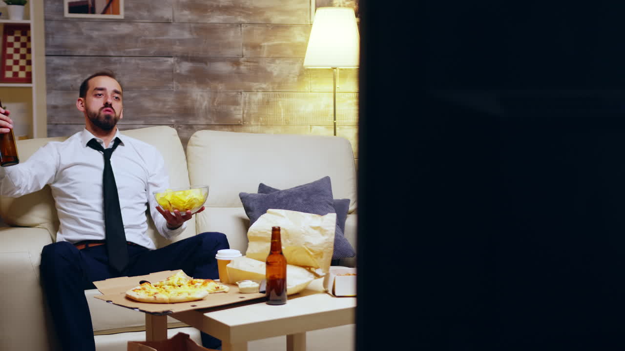 Businessman still in his suit sitting on couch cheering