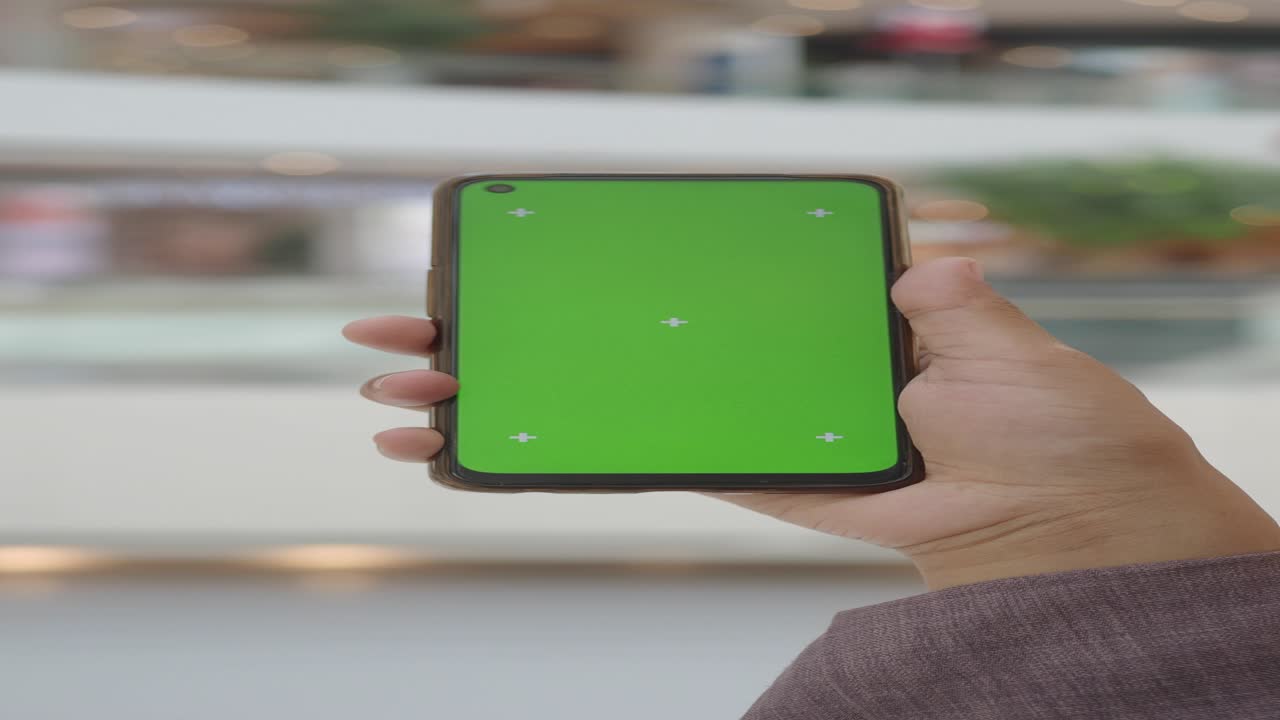 persona con un teléfono de pantalla verde en un centro comercial