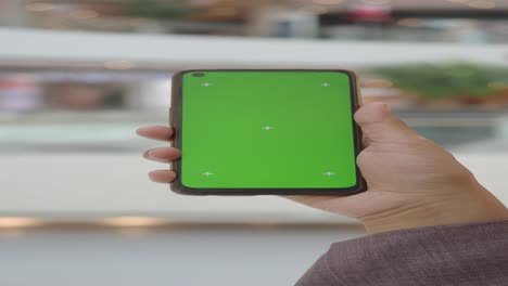 persona con un teléfono de pantalla verde en un centro comercial