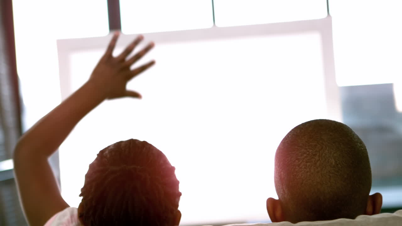 hermanos felices animando en la televisión en el sofá