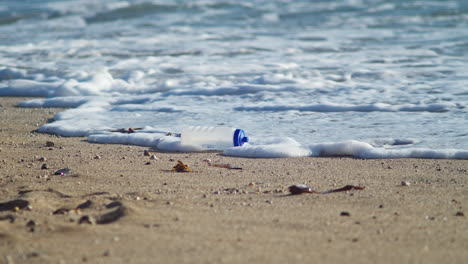 Plastic-Tumbler-Washed-Ashore-On-The-Sandy-Beach-Of-Little-Fistral,-Newquay,-Cornwall,-UK