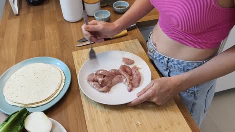 woman preparing chicken for tortillas