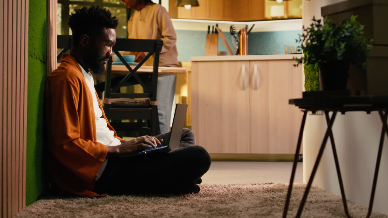 African American person, browsing on laptop, cozy moment, on floor hallway