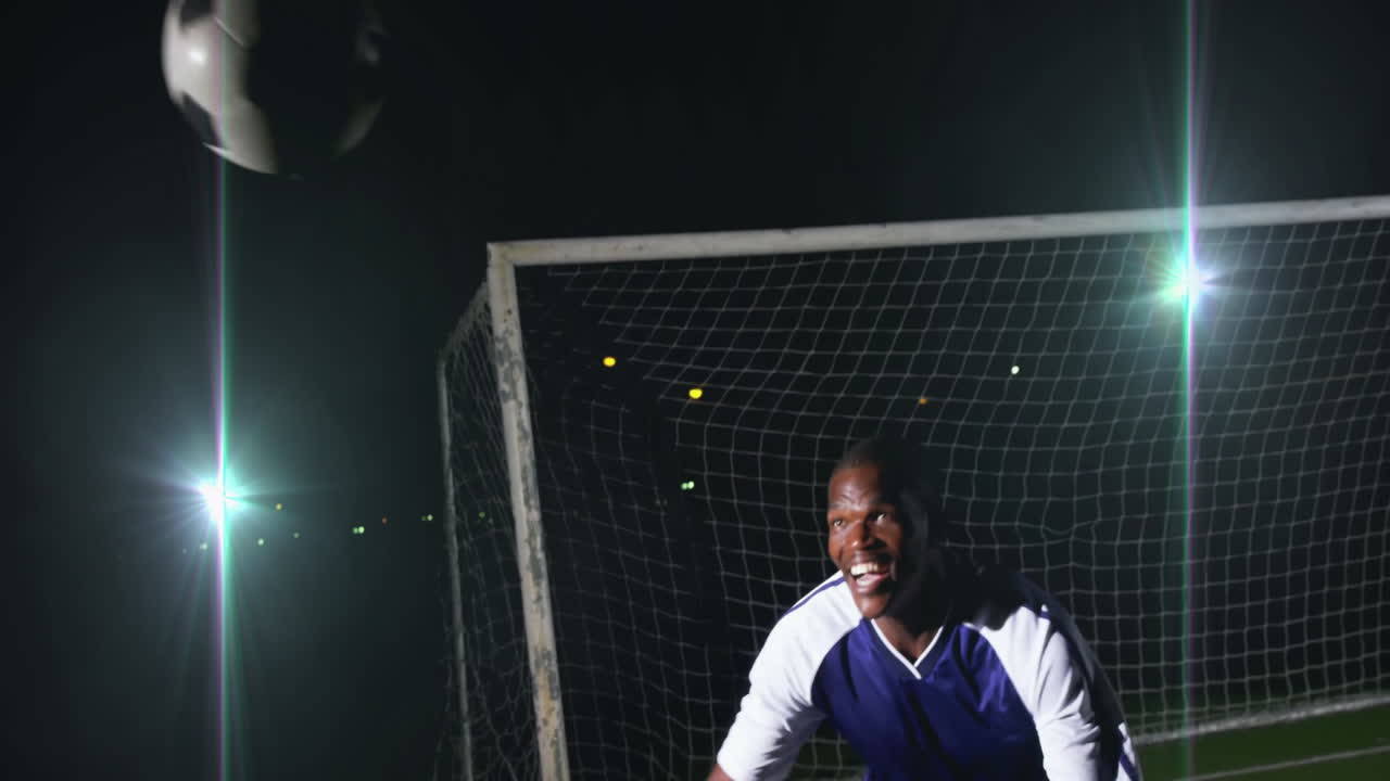 Celebrating in front of goal at night, soccer player in blue jersey