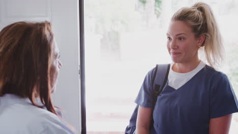 middle aged women talking to visiting female healthcare worker at her front door