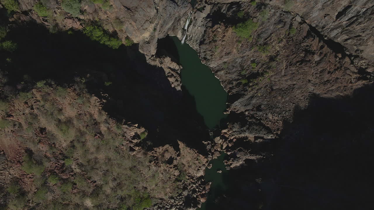 4K bird’s eye view drone footage overflying the canyon in Namibia’s Namib region, revealing a tranquil lake below. The stunning contrast between the canyon’s rugged cliffs and the serene lake