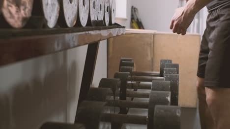 a strong man picks up a pair of weights from a row of dumbbells