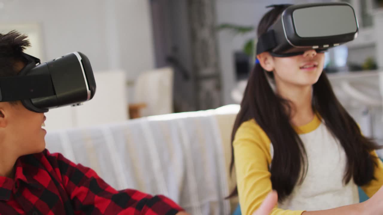 hermano y hermana asiáticos felices en casa, sentados en el sofá en la sala de estar divirtiéndose usando auriculares vr