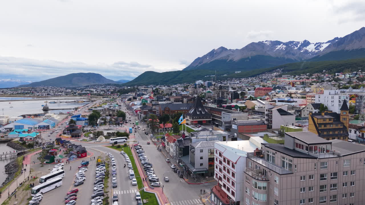 Travlt havneområde med stejle bjerge, der rejser sig bag et bylandskab i Ushuaia, Argentina. Luftfoto fra drone.