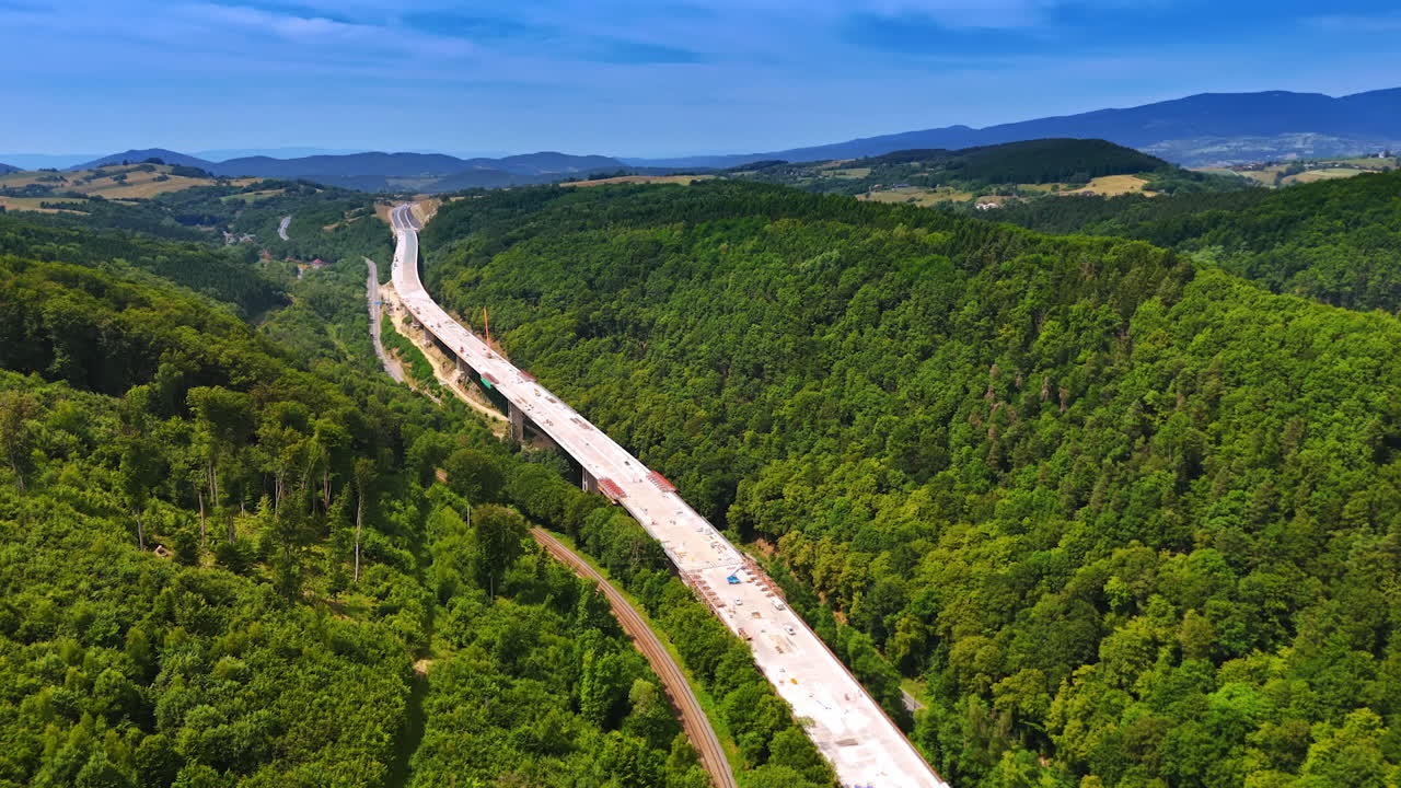 New highway through forest. Workers build a highway through lush hills under a clear sky, blending nature and development