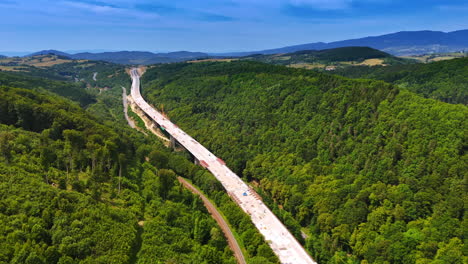 new highway through forest. workers build a highway through lush hills under a clear sky, blending nature and development