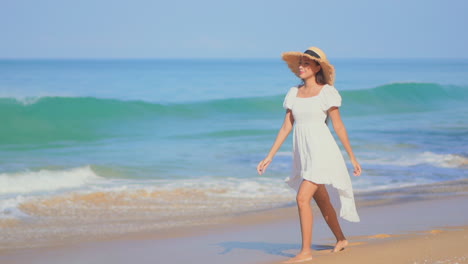 Junge-Frau-In-Weißem-Kleid-Und-Hut-Geht-Barfuß-Am-Meer