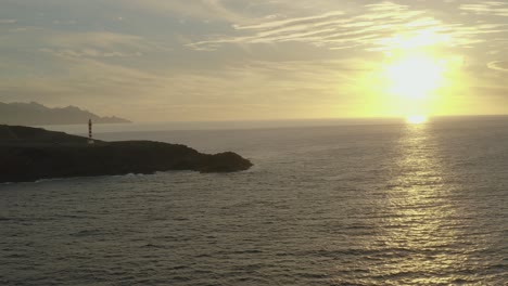 drone tiro panorama de um farol na hora de ouro com oceano e sol ao fundo