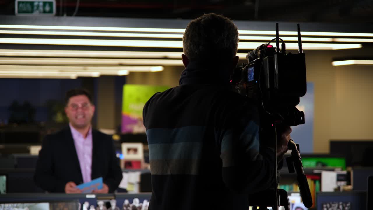 operador de televisión en el canal de producción de radiodifusión de televisión. operador de cámara en la sala de noticias disparar película de medios. camarógrafo trabajando en estudio de televisión producción de video entrevista de filmación. hacer programa de televisión o película.