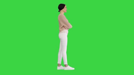 young smiling woman waving her hand as a greeting looking at the camera on a green screen, chroma key