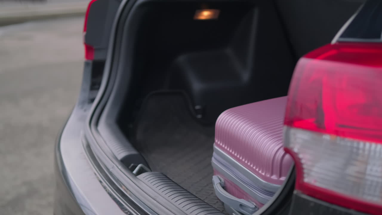 mujer cargando una maleta en el maletero del coche