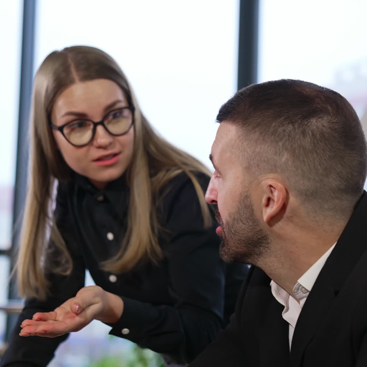Young female employee persuading colleagues pointing at papers. Discussing ideas and making suggestions in a big office
