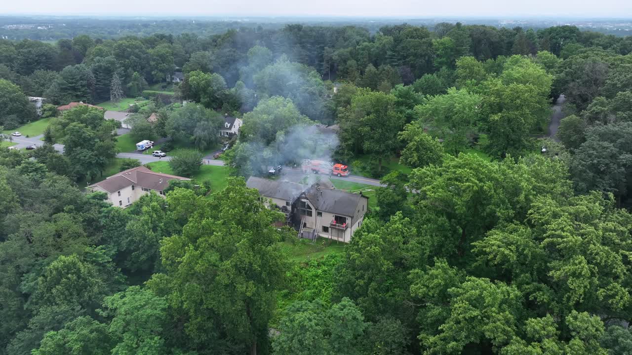 Luftaufnahme eines brennenden Hauses in einem ruhigen amerikanischen Vorort, Rauch steigt durch Bäume auf. Notfallszene in einem Wohngebiet. Dramatische, reale Katastrophe in einer amerikanischen Stadt. Weitwinkelaufnahme