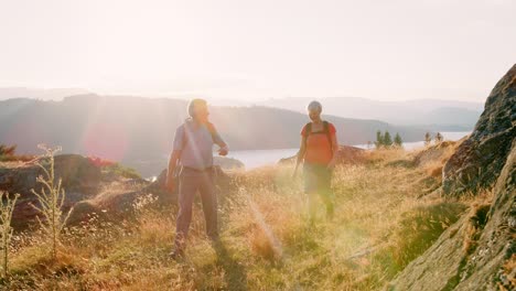 slow motion shot of senior couple walking on top of hill on hike through beautiful countryside in lake district uk