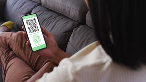 mujer en casa con un teléfono inteligente con certificado de vacunación contra la covid y código qr en la pantalla
