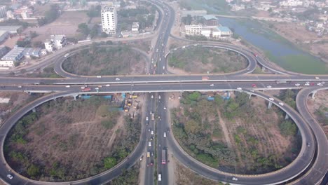 cinematic aerial view of the iconic cloverleaf interchange of maduravoyal flyover bridge in chennai captured by drone under smoggy and hazy morning with smooth flowing traffic