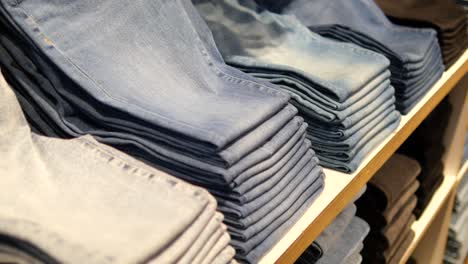 stacks of jeans on shelves in clothing store