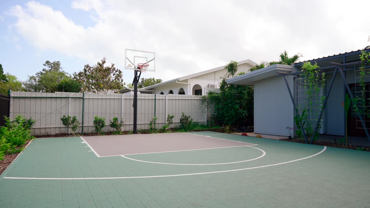 современный тропический дом с просторным задним двором с теннисным кортом, пышной зеленью и открытым пространством для спорта