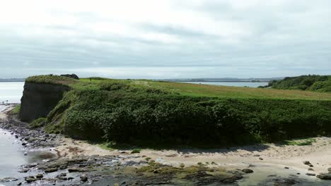 sunny welsh coastal penrhos meadow headland overlooking rocky seafront beach aerial view